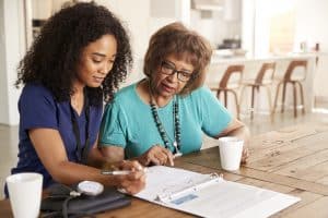 Female Healthcare Worker Filling In A Form With A Senior Woman